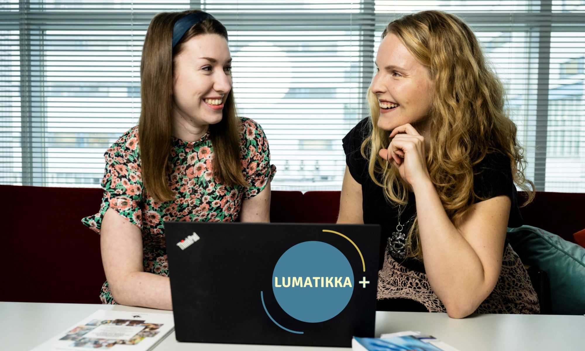 Kuvassa Alisa Uusi-Kilponen ja Eveliina Hietakymi, jotka katsovat toisiaan. Edessä tietokone ja vieressä vasemmassa nurkassa LUMATIKKA+-logo.
